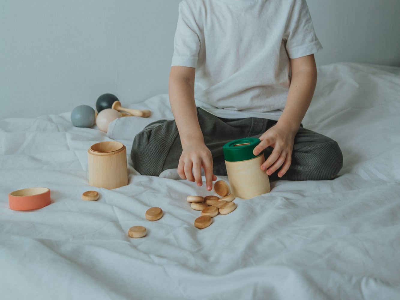 Kinderhände stecken Holzmünzen in eine Dose